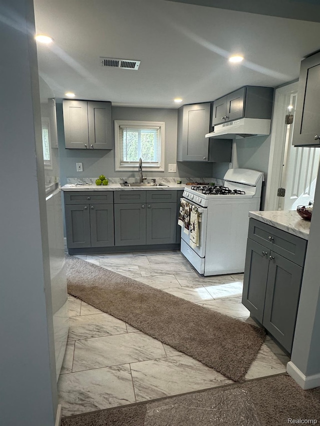 17788 Quarry St, Riverview, MI 48193 - kitchen with gas range gas stove, gray cabinetry, under cabinet range hood, light marble finish flooring, and recessed lighting