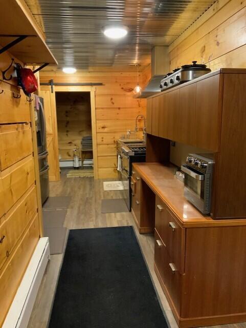 777 W Lincoln Ave, White Cloud, MI 49349 - kitchen with light wood-style floors, brown cabinetry, stainless steel appliances, light countertops, and wooden walls