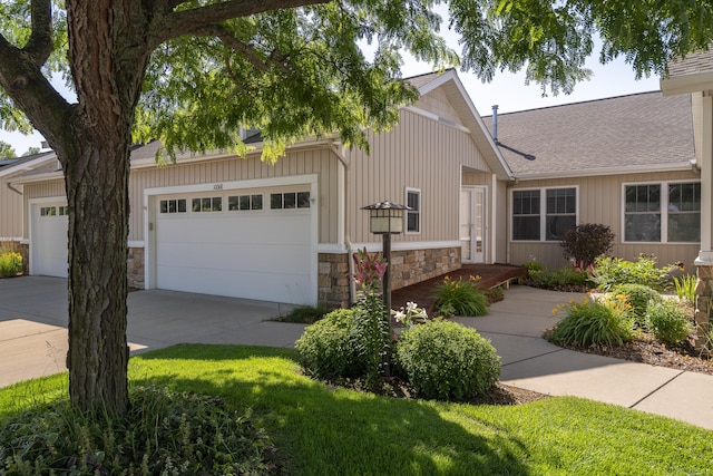 10068 S Crossroads Cir SE, Caledonia, MI 49316 - view of front of property featuring stone siding, concrete driveway, an attached garage, and roof with shingles
