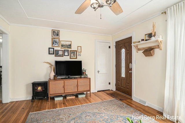 1314 Grant St, Grand Haven, MI 49417 - foyer featuring wood-type flooring, a wood stove, ceiling fan, and ornamental molding