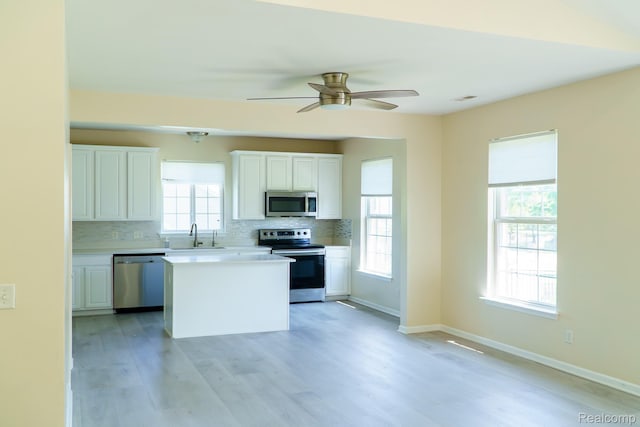 1803 Pinecroft Dr, Canton, MI 48188 - kitchen featuring appliances with stainless steel finishes, white cabinets, decorative backsplash, a center island, and light wood-style floors
