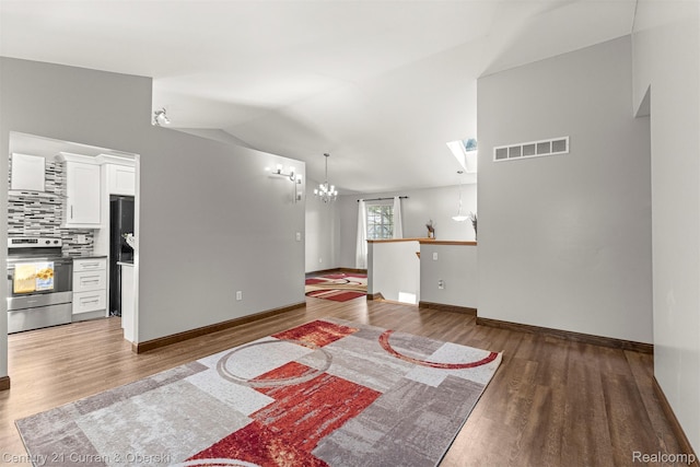1786 Daisy Ln, Westland, MI 48186 - unfurnished living room featuring wood finished floors, vaulted ceiling, and a chandelier