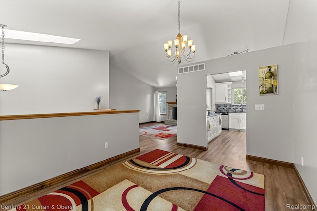 1786 Daisy Ln, Westland, MI 48186 - living area with light wood finished floors, a skylight, a chandelier, and lofted ceiling