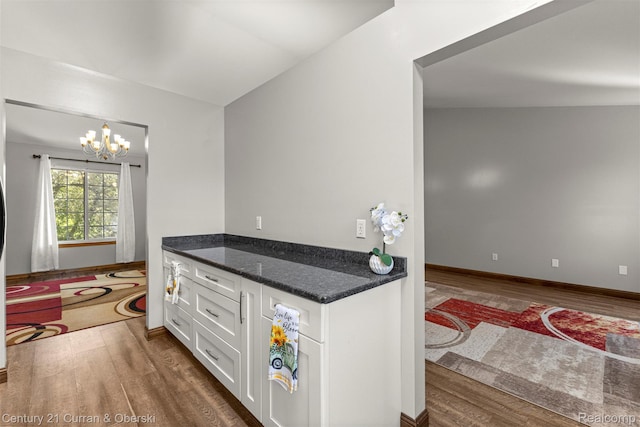 1786 Daisy Ln, Westland, MI 48186 - kitchen with dark wood finished floors, white cabinetry, a chandelier, dark stone counters, and pendant lighting