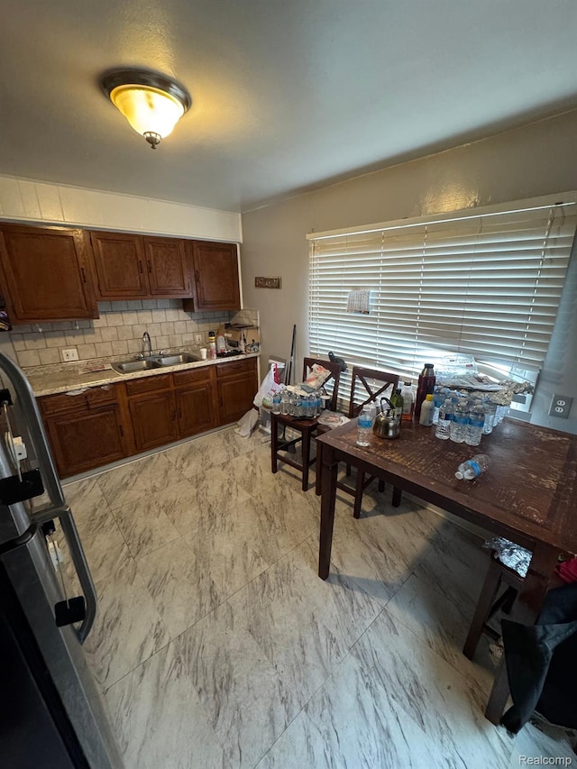 8116 Wyoming St, Detroit, MI 48204 - kitchen with backsplash, light countertops, light marble finish floors, brown cabinets, and fridge