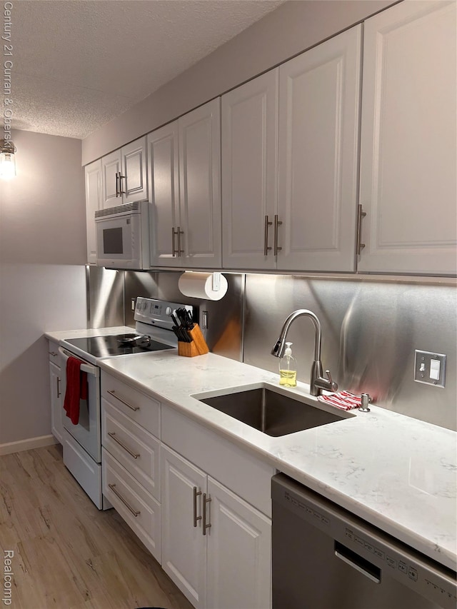 21800 Morley Ave Unit 607, Dearborn, MI 48124 - kitchen with white appliances, white cabinets, light wood-style floors, a textured ceiling, and light stone counters