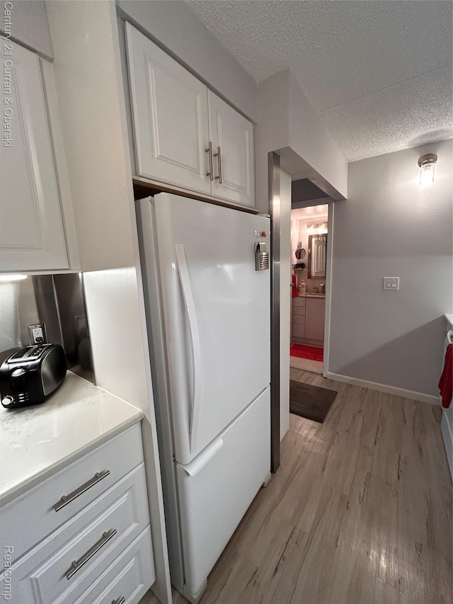 21800 Morley Ave Unit 607, Dearborn, MI 48124 - kitchen featuring freestanding refrigerator, light wood-style floors, white cabinetry, a textured ceiling, and light countertops