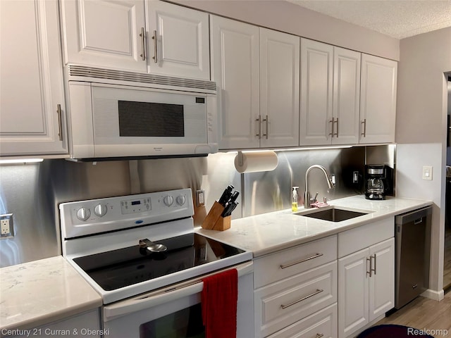 21800 Morley Ave Unit 607, Dearborn, MI 48124 - kitchen with white appliances, white cabinets, light countertops, a textured ceiling, and light wood-style floors