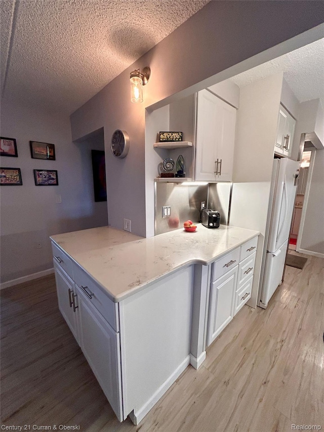 21800 Morley Ave Unit 607, Dearborn, MI 48124 - kitchen with a textured ceiling, light wood finished floors, white cabinetry, and freestanding refrigerator
