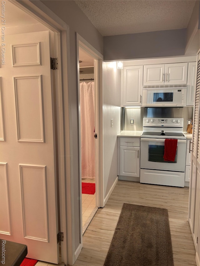 21800 Morley Ave Unit 607, Dearborn, MI 48124 - kitchen with white appliances, white cabinets, light wood-style flooring, light countertops, and a textured ceiling