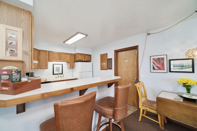 5015 Main St, Onekama, MI 49675 - kitchen with freestanding refrigerator, a peninsula, light countertops, and a breakfast bar area