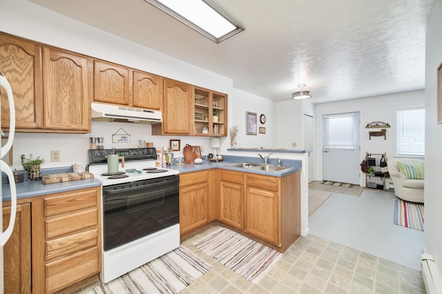 5015 Main St, Onekama, MI 49675 - kitchen with white electric range, under cabinet range hood, a peninsula, baseboard heating, and light countertops