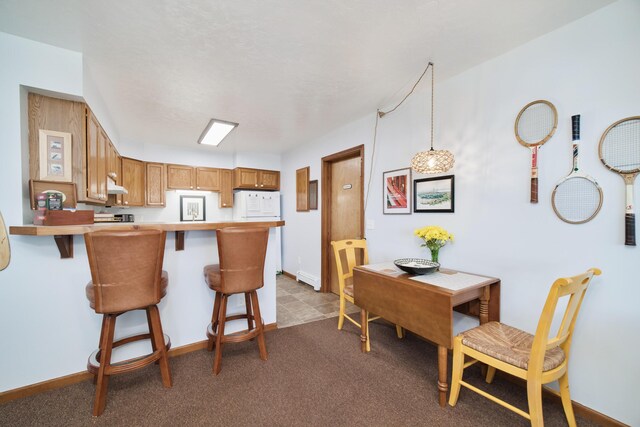 5015 Main St, Onekama, MI 49675 - kitchen with a peninsula, a kitchen bar, light countertops, and brown cabinetry