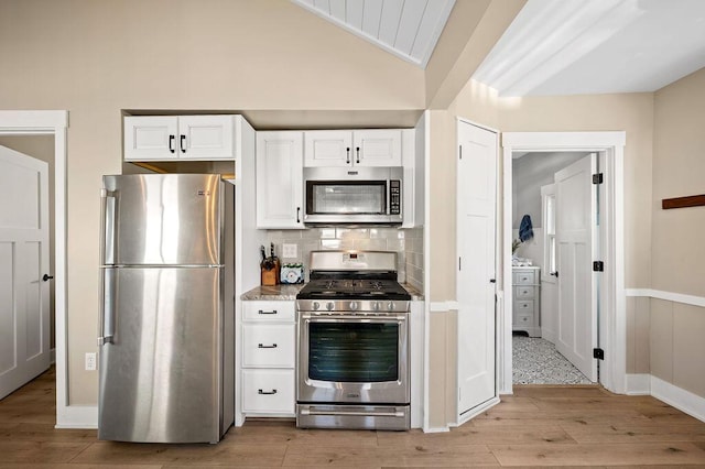 31326 Curran Beach Rd, Dowagiac, MI 49047 - kitchen featuring appliances with stainless steel finishes, light wood finished floors, white cabinetry, vaulted ceiling, and tasteful backsplash