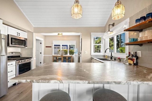 31326 Curran Beach Rd, Dowagiac, MI 49047 - kitchen with stainless steel appliances, lofted ceiling, a peninsula, a breakfast bar, and white cabinetry
