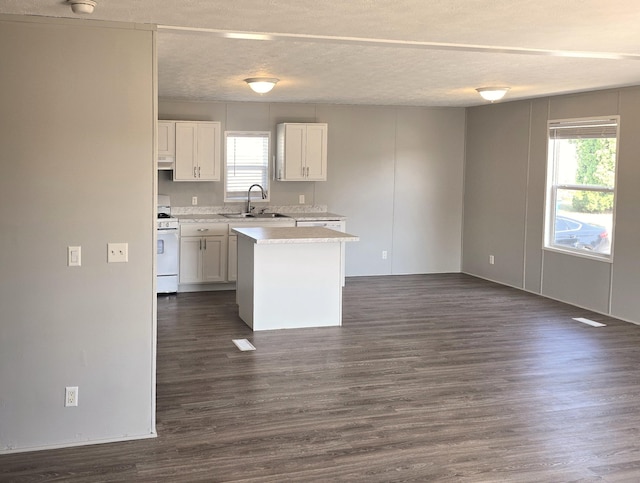 26 Traveler Dr Unit 26, Sparta, MI 49345 - kitchen featuring dark wood finished floors, white range with gas cooktop, white cabinets, light countertops, and healthy amount of natural light