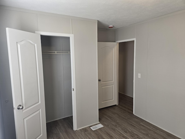 26 Traveler Dr Unit 26, Sparta, MI 49345 - unfurnished bedroom featuring dark wood-style flooring, a textured ceiling, and a closet