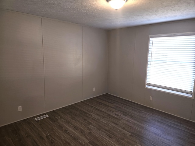 26 Traveler Dr Unit 26, Sparta, MI 49345 - spare room featuring a textured ceiling, dark wood-type flooring, plenty of natural light, and a decorative wall