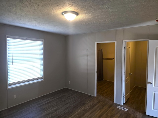 26 Traveler Dr Unit 26, Sparta, MI 49345 - unfurnished bedroom with a textured ceiling, dark wood-style flooring, a spacious closet, and a closet