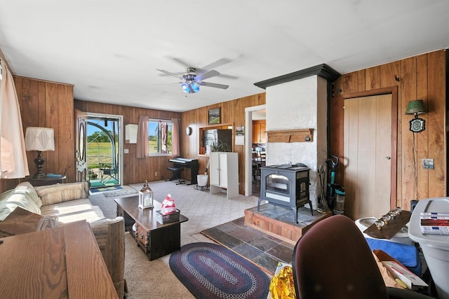 8698 Big Stone Lake Rd, Evart, MI 49631 - carpeted living room featuring wooden walls, a wood stove, and a ceiling fan