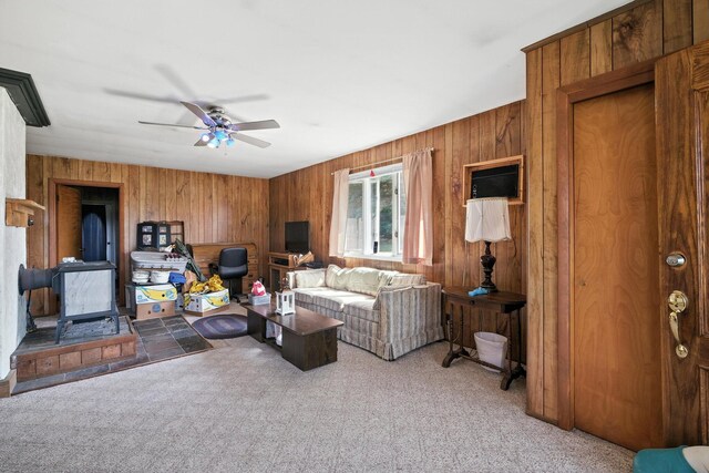 8698 Big Stone Lake Rd, Evart, MI 49631 - living area featuring a wood stove, carpet, ceiling fan, and wooden walls