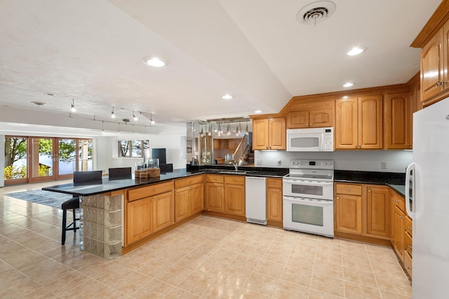 15665 Portage Rd, Vicksburg, MI 49097 - kitchen with white appliances, a peninsula, a kitchen bar, recessed lighting, and dark countertops