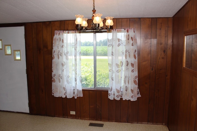 2786 Dinius Rd, Tecumseh, MI 49286 - unfurnished dining area featuring a chandelier, wood walls, and carpet