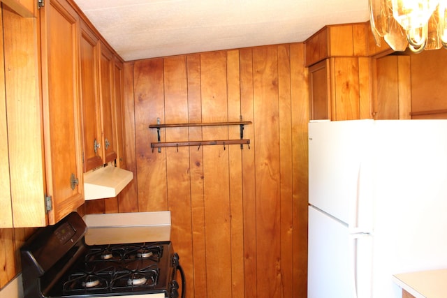 2786 Dinius Rd, Tecumseh, MI 49286 - kitchen featuring freestanding refrigerator, gas stove, ventilation hood, brown cabinets, and wooden walls