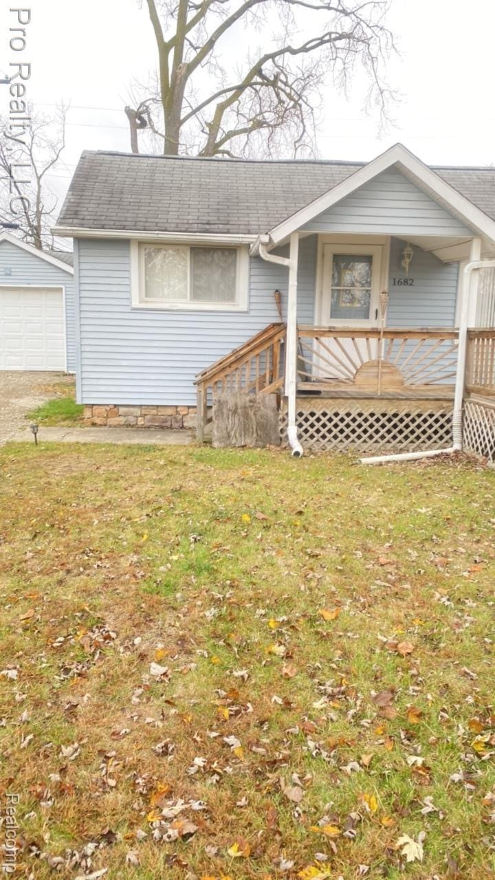 1682 Beatrice St, Westland, MI 48186 - view of front of property with a detached garage, roof with shingles, a front lawn, and driveway