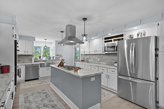 11560 Thrush Dr, Lakeview, MI 48850 - kitchen featuring appliances with stainless steel finishes, island range hood, decorative backsplash, and light wood-type flooring