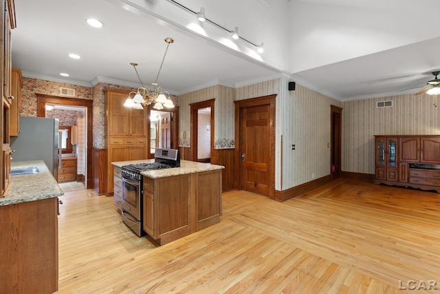 305 W Chicago Blvd, Tecumseh, MI 49286 - kitchen featuring appliances with stainless steel finishes, wallpapered walls, light wood-style flooring, a kitchen island, and brown cabinetry
