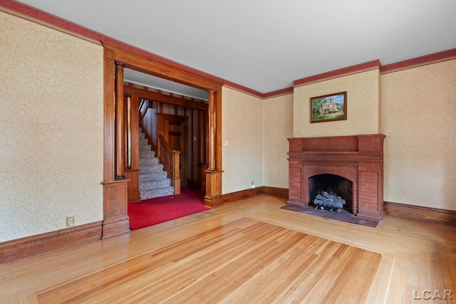 305 W Chicago Blvd, Tecumseh, MI 49286 - unfurnished living room with wood-type flooring, a fireplace with flush hearth, stairs, ornamental molding, and wallpapered walls
