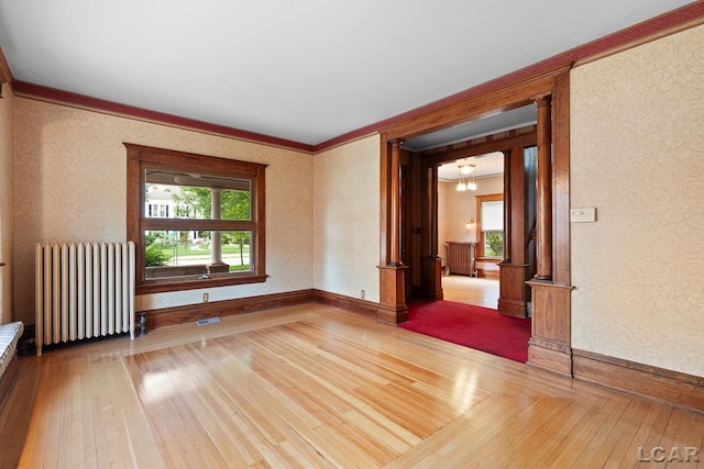 305 W Chicago Blvd, Tecumseh, MI 49286 - empty room with radiator heating unit, ornate columns, hardwood / wood-style floors, healthy amount of natural light, and ornamental molding