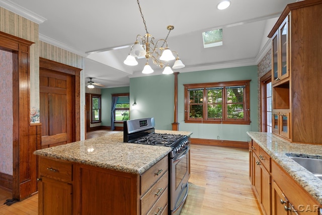 305 W Chicago Blvd, Tecumseh, MI 49286 - kitchen with stainless steel gas stove, light wood-style floors, brown cabinets, a chandelier, and healthy amount of natural light