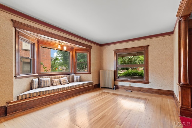 305 W Chicago Blvd, Tecumseh, MI 49286 - unfurnished room featuring radiator heating unit, ornate columns, hardwood / wood-style floors, ornamental molding, and wallpapered walls