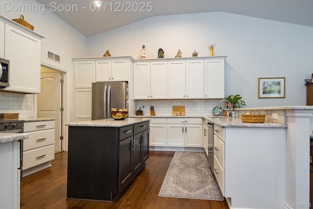 1079 Hampshire Ct, Rochester, MI 48307 - kitchen with stainless steel appliances, white cabinets, dark wood-style floors, decorative backsplash, and lofted ceiling