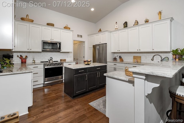 1079 Hampshire Ct, Rochester, MI 48307 - kitchen with stainless steel appliances, white cabinetry, tasteful backsplash, a kitchen breakfast bar, and lofted ceiling