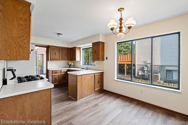 37746 Juniper Dr, Sterling Heights, MI 48310 - kitchen with a peninsula, light wood-style floors, light countertops, a chandelier, and brown cabinetry