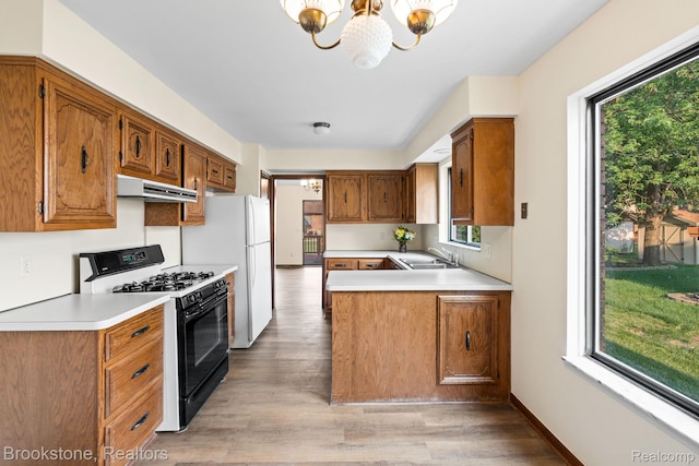 37746 Juniper Dr, Sterling Heights, MI 48310 - kitchen featuring black gas range oven, under cabinet range hood, a chandelier, light wood-type flooring, and light countertops