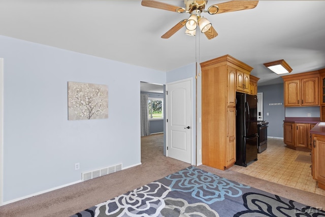 4100 Hunt Rd, Adrian, MI 49221 - kitchen with freestanding refrigerator, light colored carpet, a ceiling fan, and brown cabinets