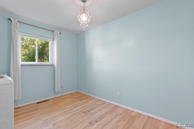 4100 Hunt Rd, Adrian, MI 49221 - unfurnished room featuring wood finished floors, a chandelier, and washer / dryer