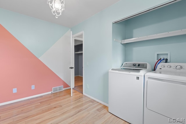 4100 Hunt Rd, Adrian, MI 49221 - washroom with washing machine and clothes dryer, light wood-style flooring, and a chandelier