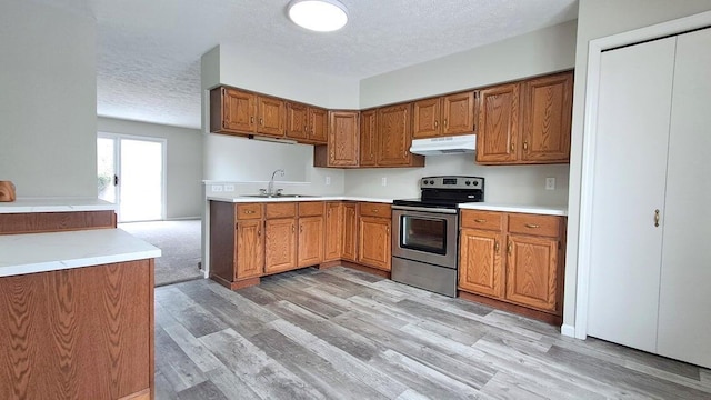 4763 Weston Ave, Kalamazoo, MI 49006 - kitchen featuring stainless steel electric range, under cabinet range hood, a textured ceiling, brown cabinets, and light wood-style floors