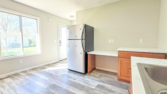 4763 Weston Ave, Kalamazoo, MI 49006 - kitchen with freestanding refrigerator, light wood-type flooring, light countertops, and brown cabinetry