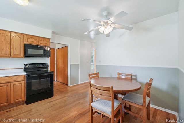 4220 England Beach Rd, White Lake, MI 48383 - dining space featuring light wood-type flooring, a ceiling fan, and a wainscoted wall