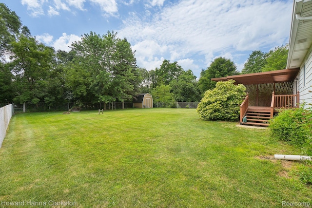 4220 England Beach Rd, White Lake, MI 48383 - fenced backyard featuring a storage unit, a deck, and view of wooded area