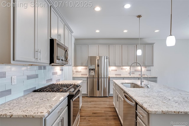 43433 Chancellor Ln, Novi, MI 48375 - kitchen with appliances with stainless steel finishes, recessed lighting, wood finished floors, tasteful backsplash, and a center island with sink