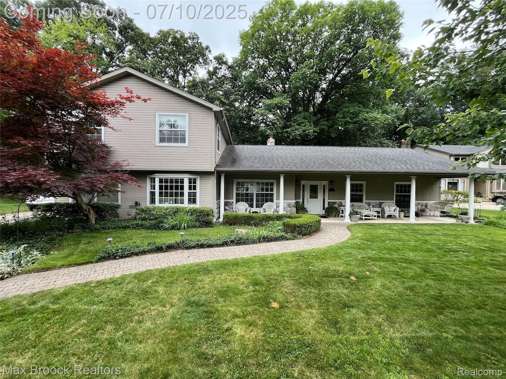 15591 Hidden Ln, Livonia, MI 48154 - view of front of house with a front yard, a chimney, and covered porch