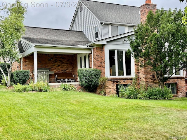 48721 W Normandy Ct, Plymouth, MI 48170 - back of house with brick siding, a lawn, a chimney, and roof with shingles