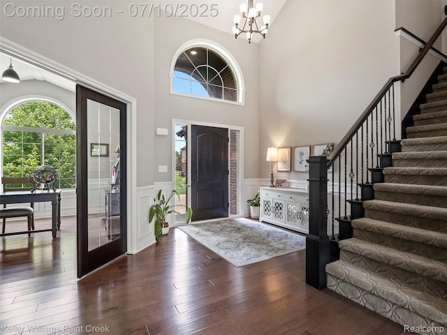 62777 Franklin Park Dr, Washington, MI 48094 - foyer featuring stairway, a chandelier, wainscoting, high vaulted ceiling, and dark wood finished floors